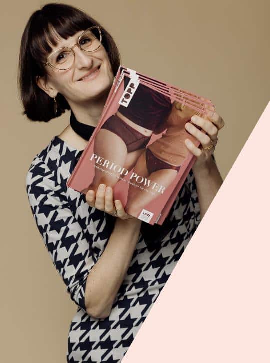 kategoriebilder_triny.de_Bücher Katriny hält mehrere Exemplare des Buches Period Power über Periodenunterwäsche und Körperwissen